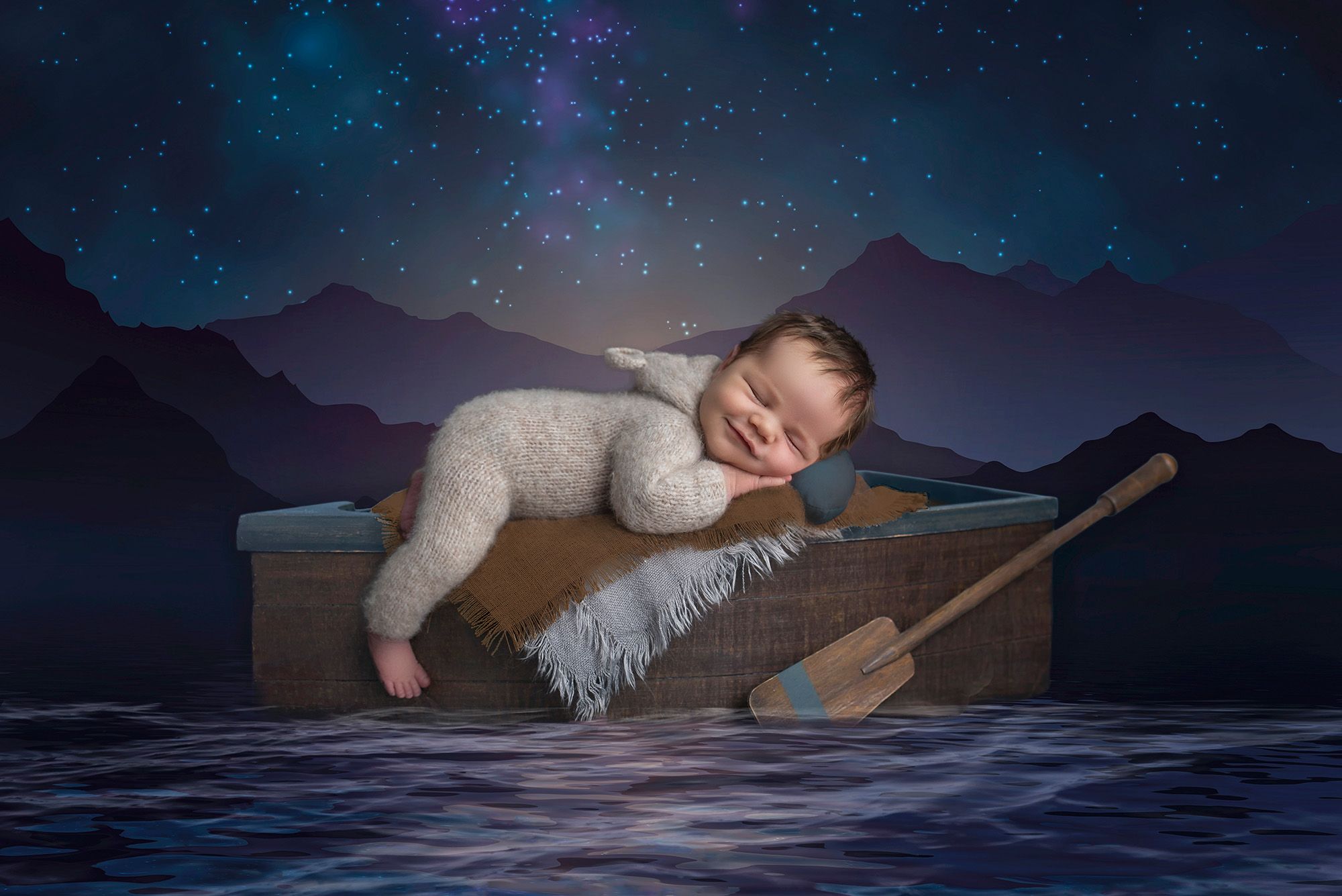 Connecticut Newborn Photography newborn baby boy asleep on row boat in sweater romper with a mountain moonlit background