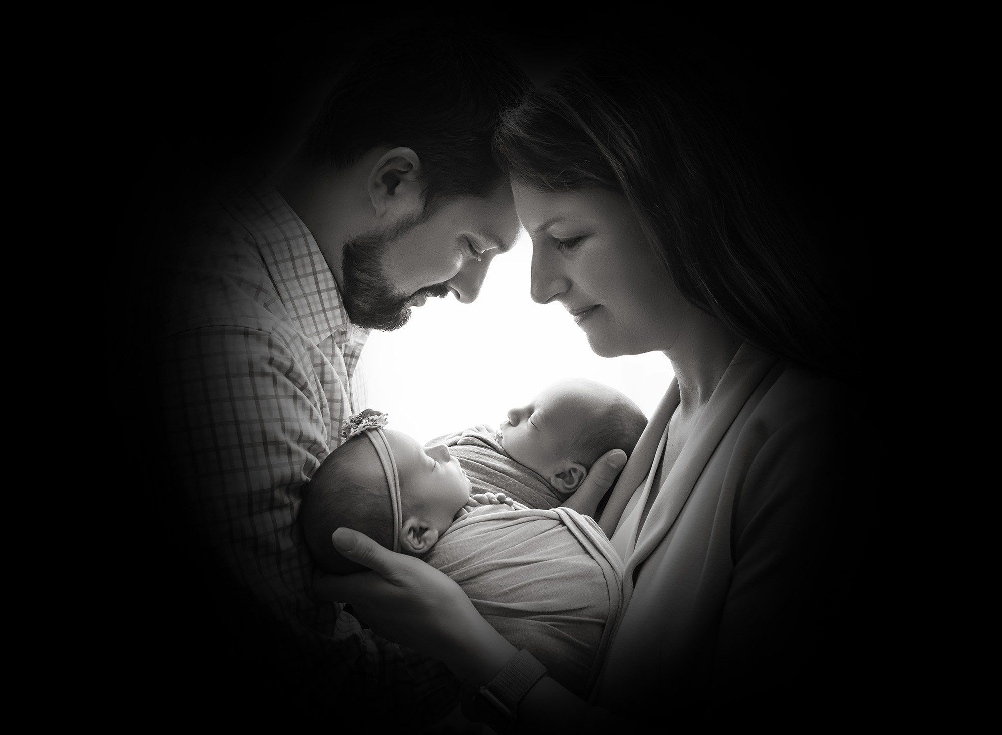 silhouette shadow of new parents face's while cradling their newborn baby boy and girl