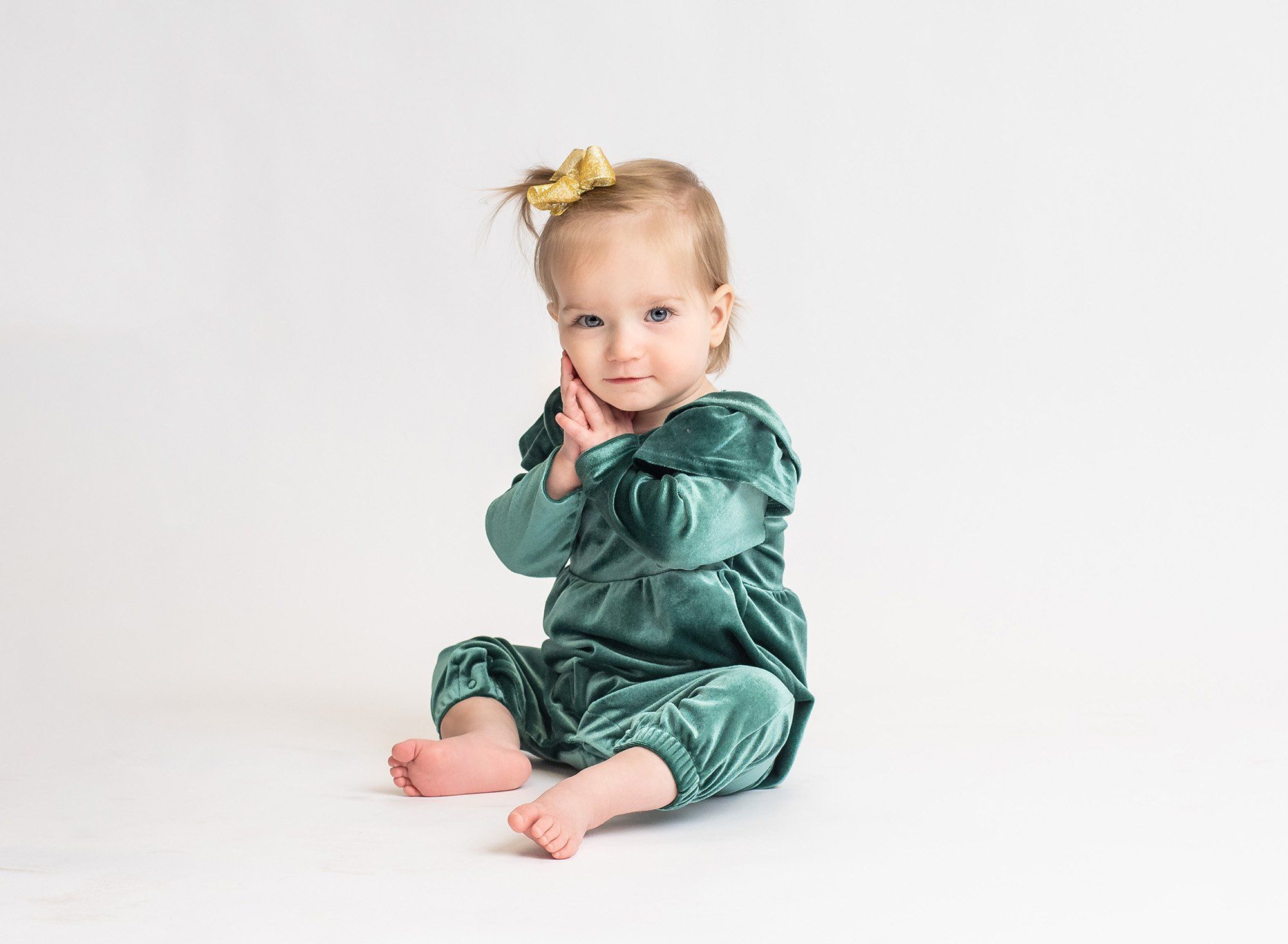 little girl looking at the camera wearing green with a white background
