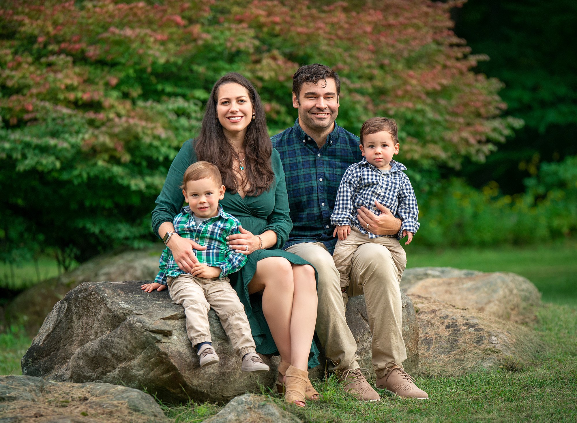 1 year old and family photography couple posing with young sons while sitting on a rock in nature