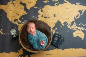baby boy sleeping in a bowl on a world map with passports ready for travel