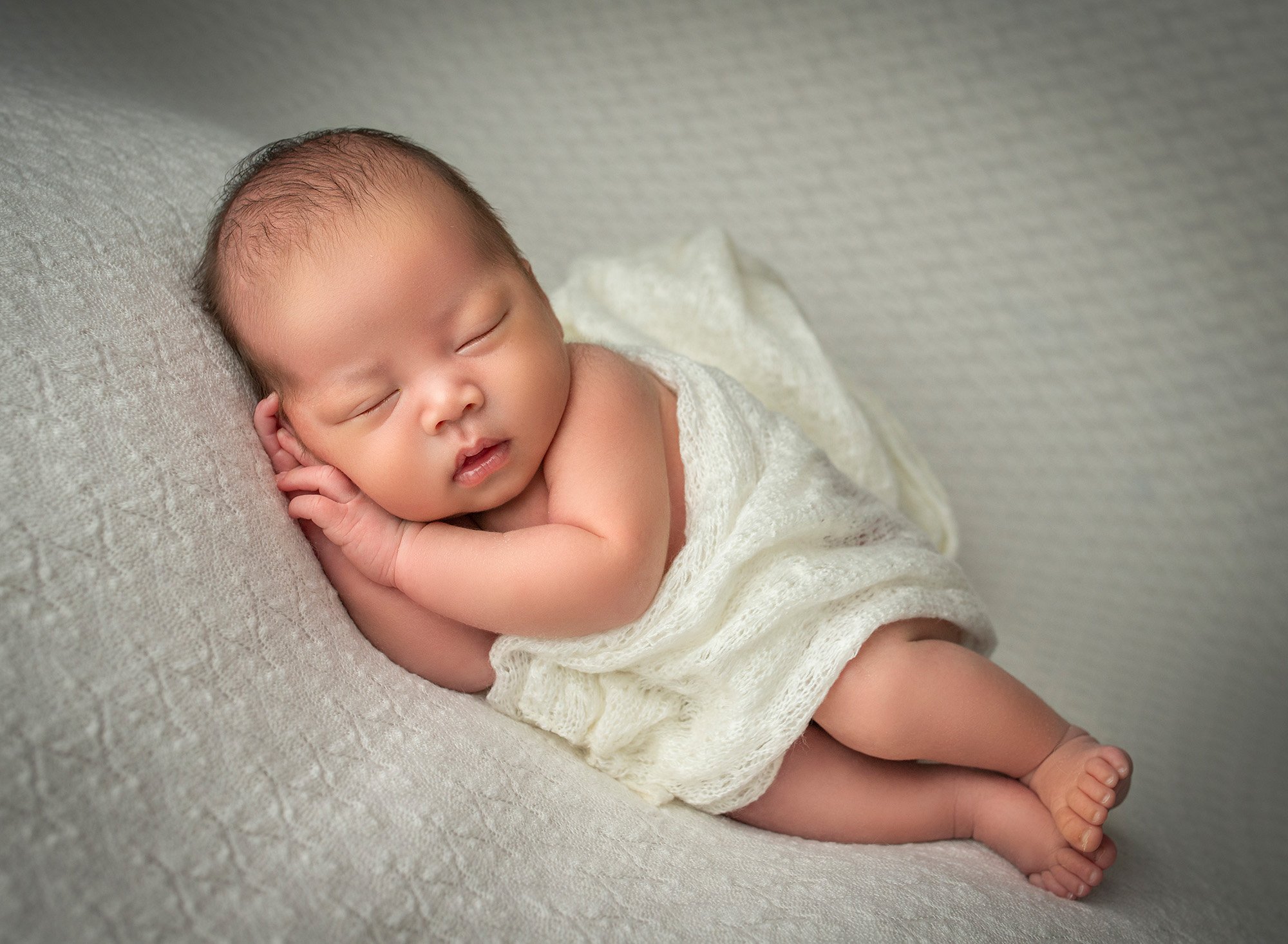 Baby Boy Newborn Photos newborn baby boy asleep on white blanket partially covered by off white wrap