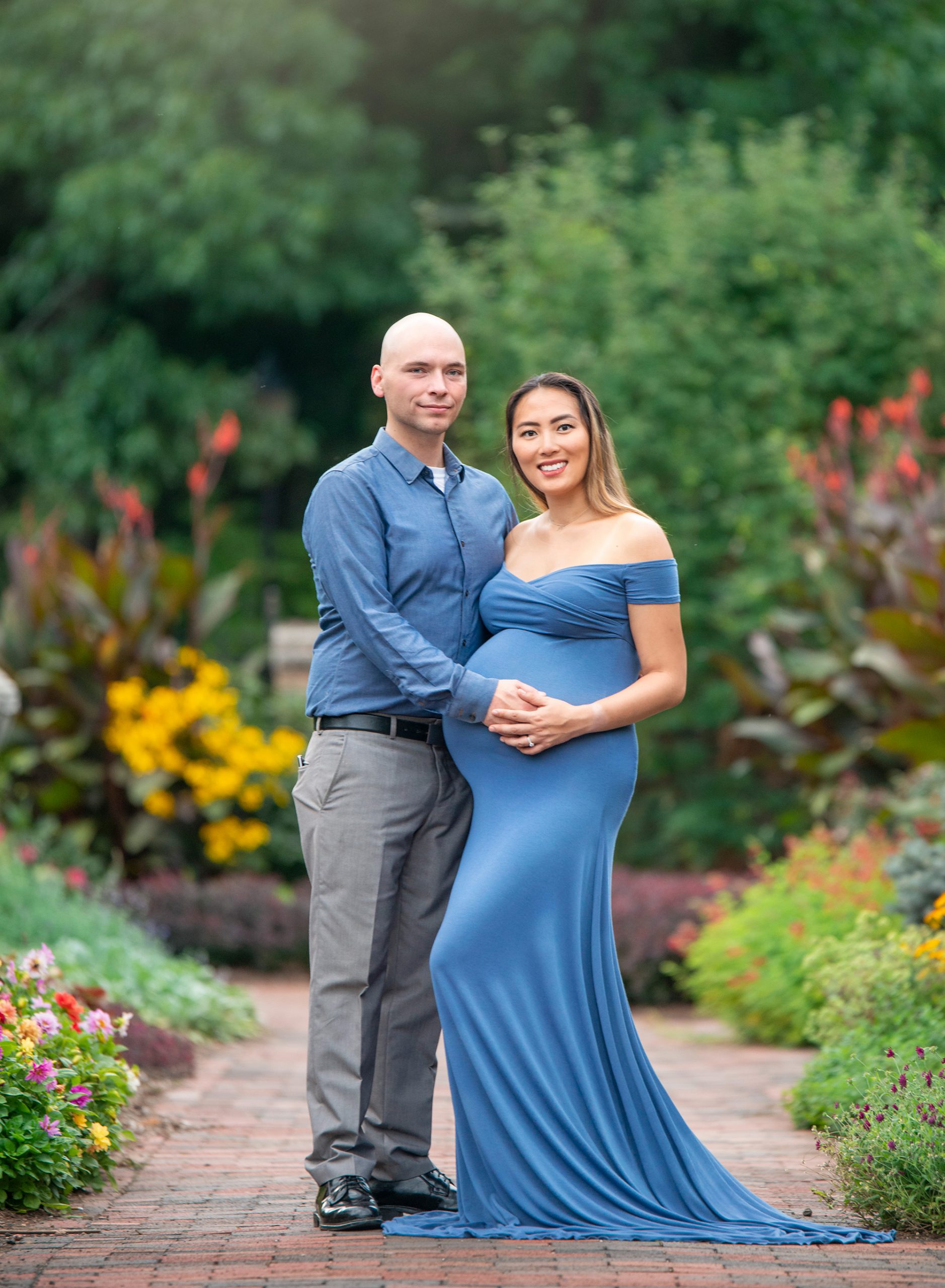 pregnant woman posing with her partner in a flower garden
