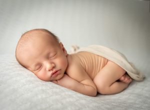 newborn baby boy laying naked on white blanket