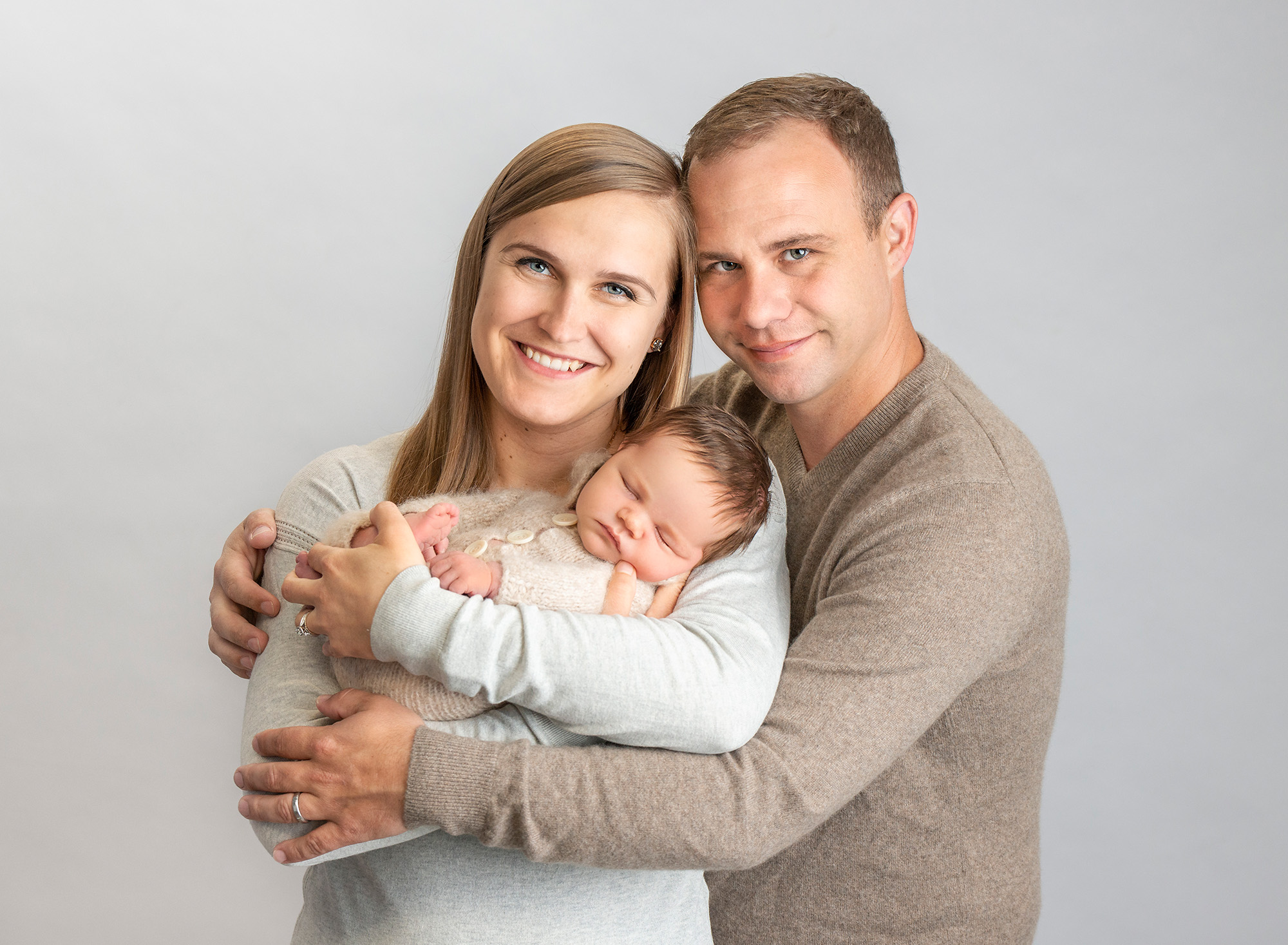 Connecticut Newborn Photography new parents smiling while cradling their newborn baby boy dressed in sweater romper
