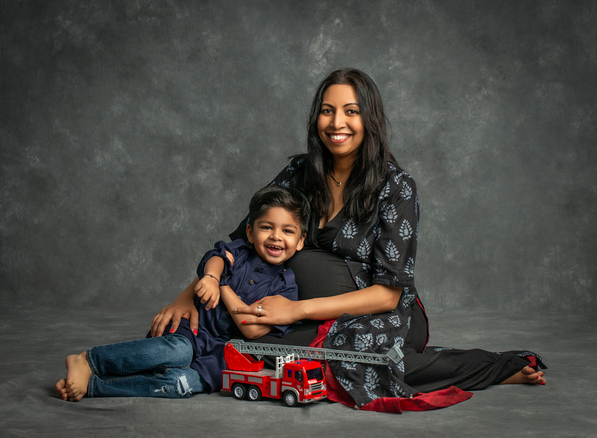 Family Maternity Photos pregnant mother posing with young son and firetruck toy