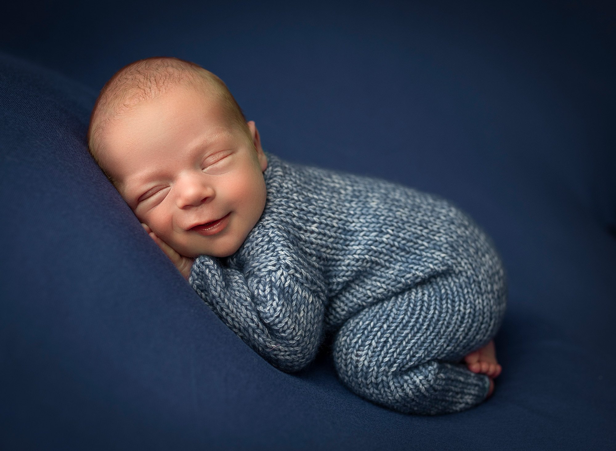 newborn baby boy asleep in blue sweater romper
