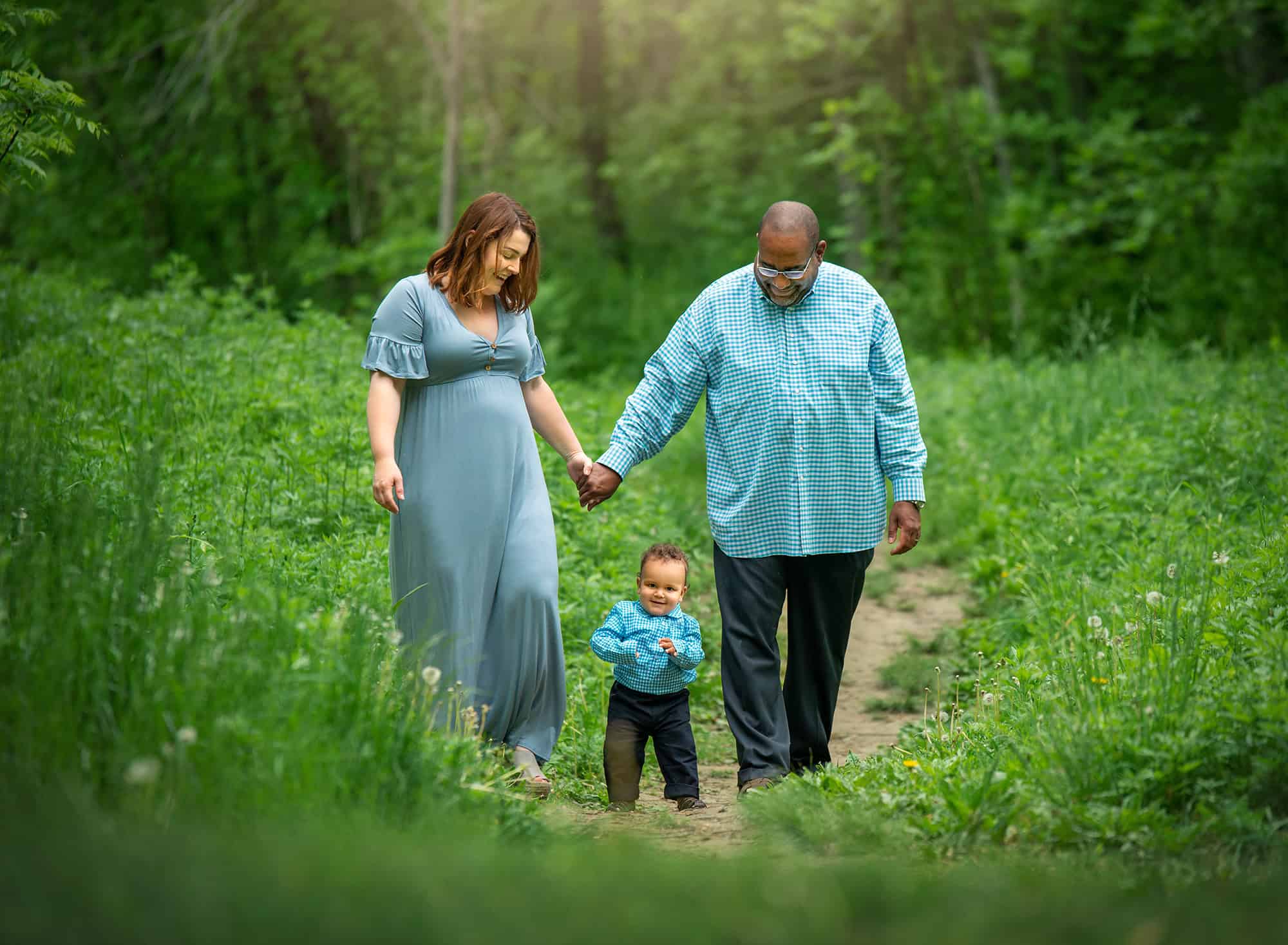 How to prepare for a family photoshoot Family Photographers in CT couple holding hands walking down path in the woods with their one year old son