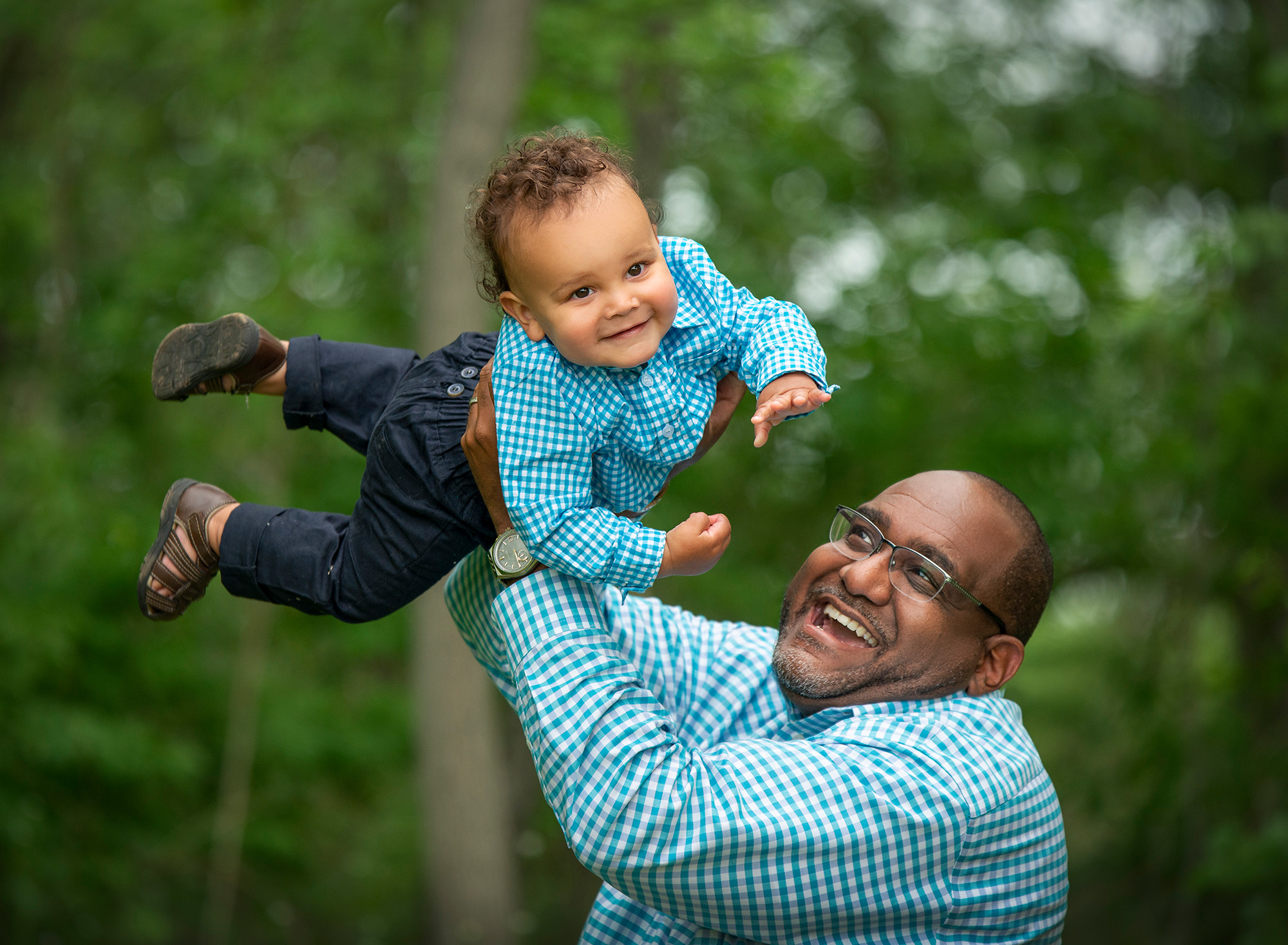 Family Photographers in CT dad holding one year old son up in the air while wearing matching shirts