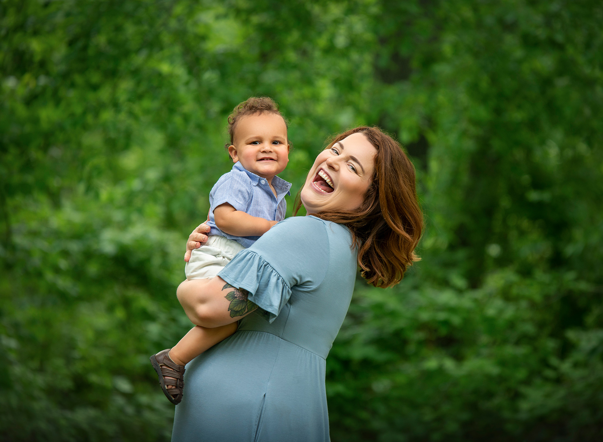 Stunning Summer Outdoor Family Photos mom smiling while holding her one year old curly haired baby boy