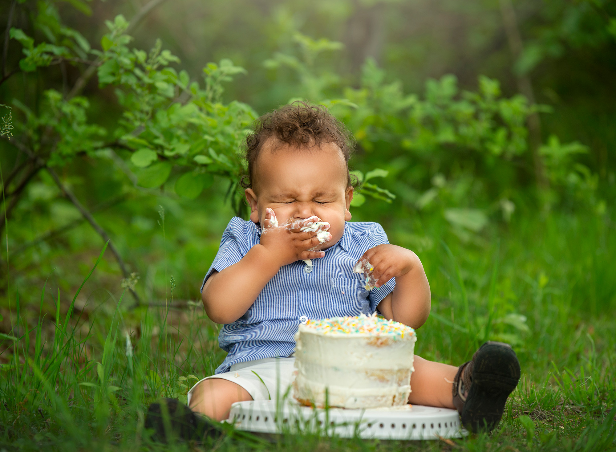 Stunning Summer Outdoor Family Photoscurly haired one year old boy eating cake