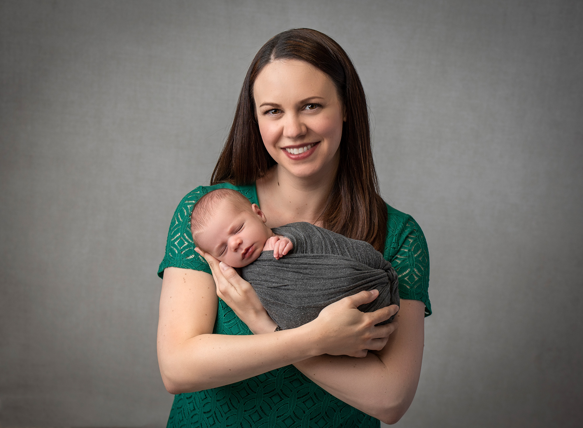 Glastonbury newborn photographer mom cradling newborn baby boy swaddled in gray