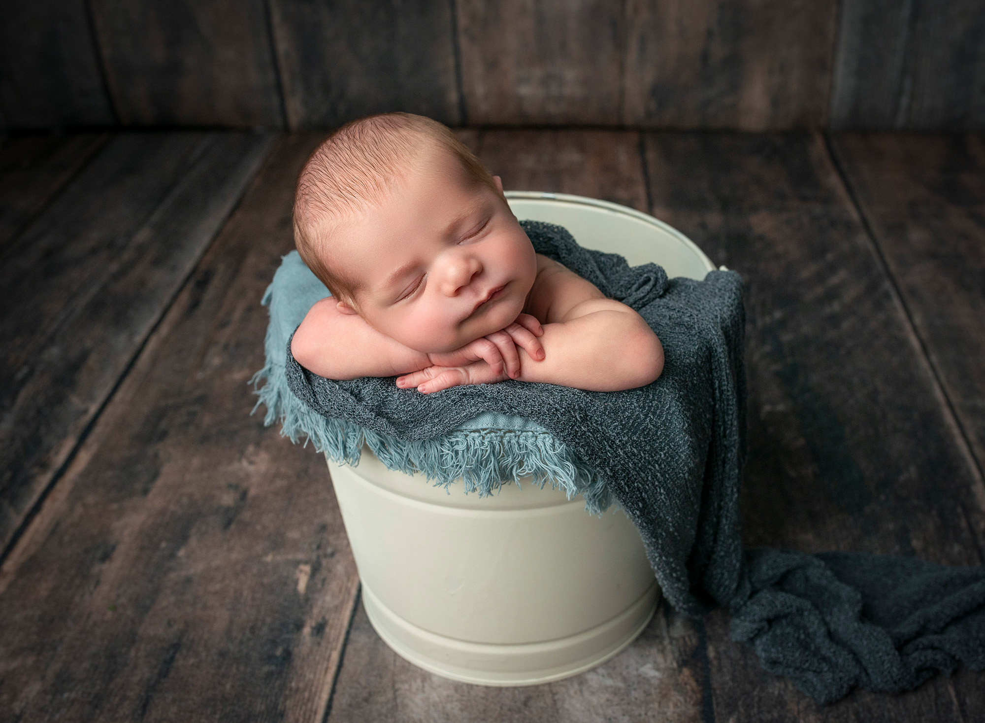 newborn baby boy asleep in white bucket with blue blankets