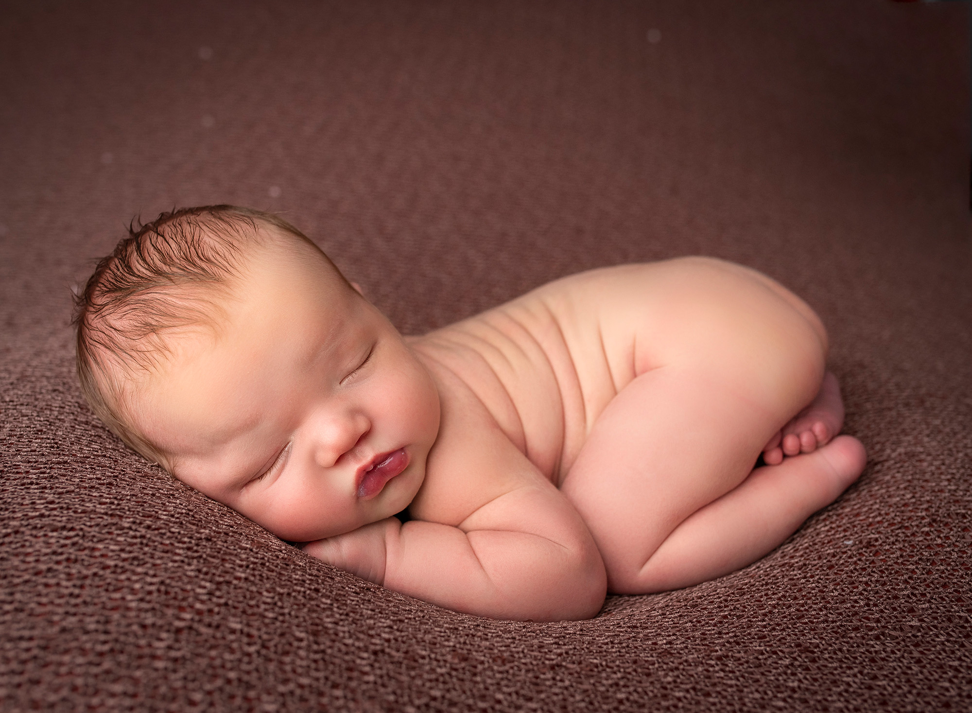 asleep naked newborn baby boy on rustic brown blanket