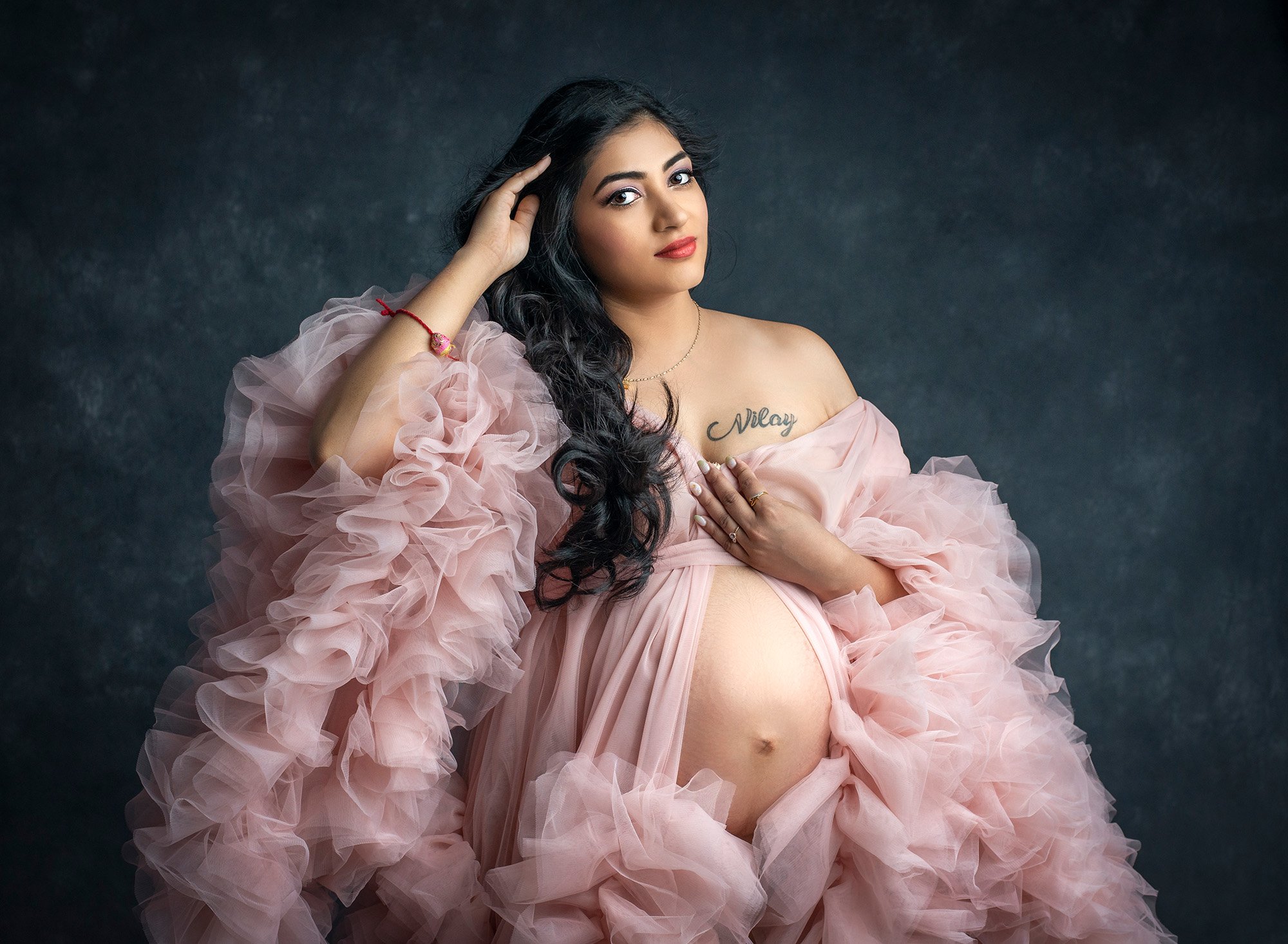 Indian Goddess Maternity photographs pregnant woman wearing ruffled pink dress exposing pregnant stomach