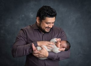 dad looking down on newborn son with hand on his stomach
