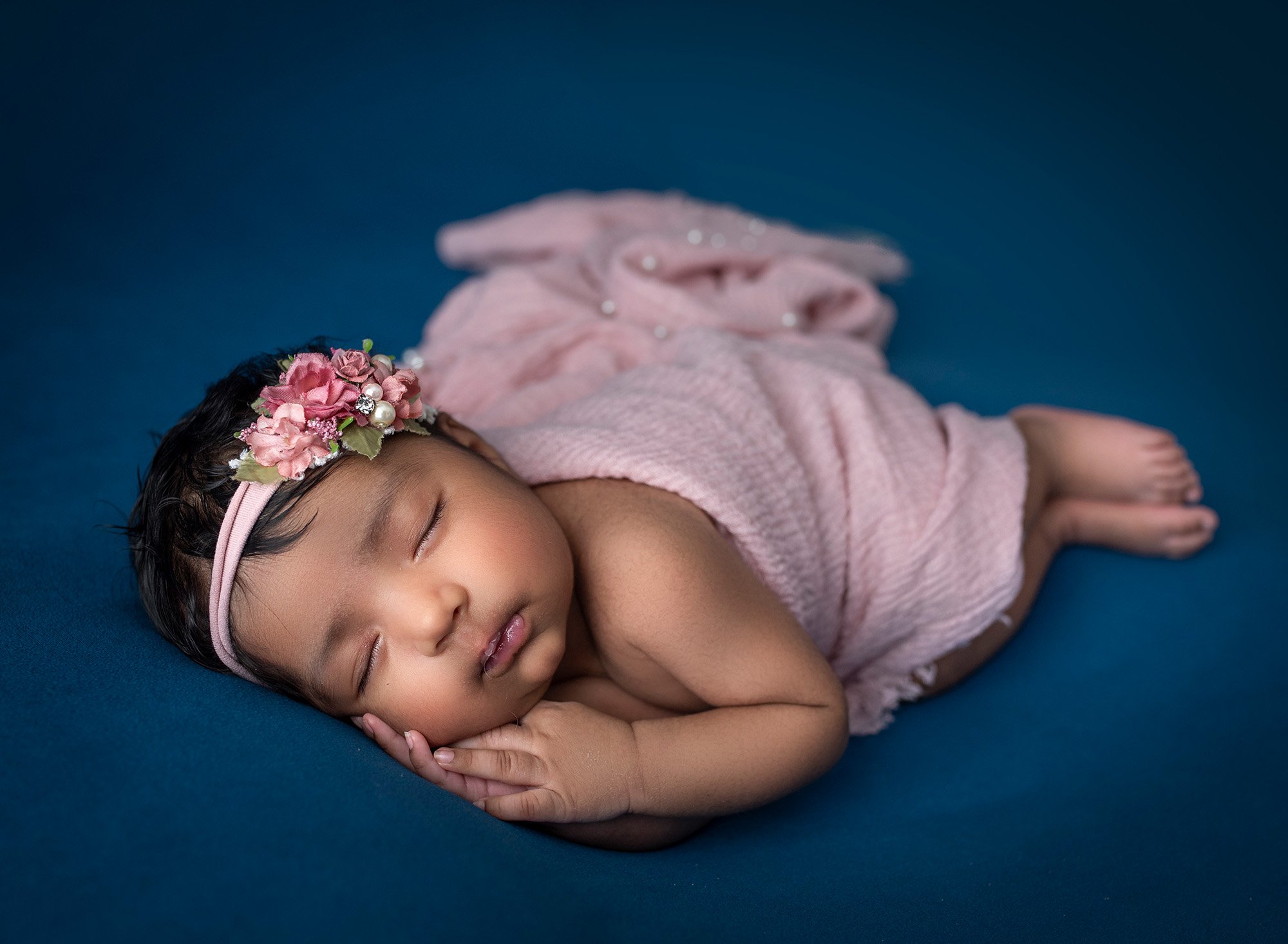Newborn Girl Photography newborn baby girl asleep on blue blanket wearing pink floral headband
