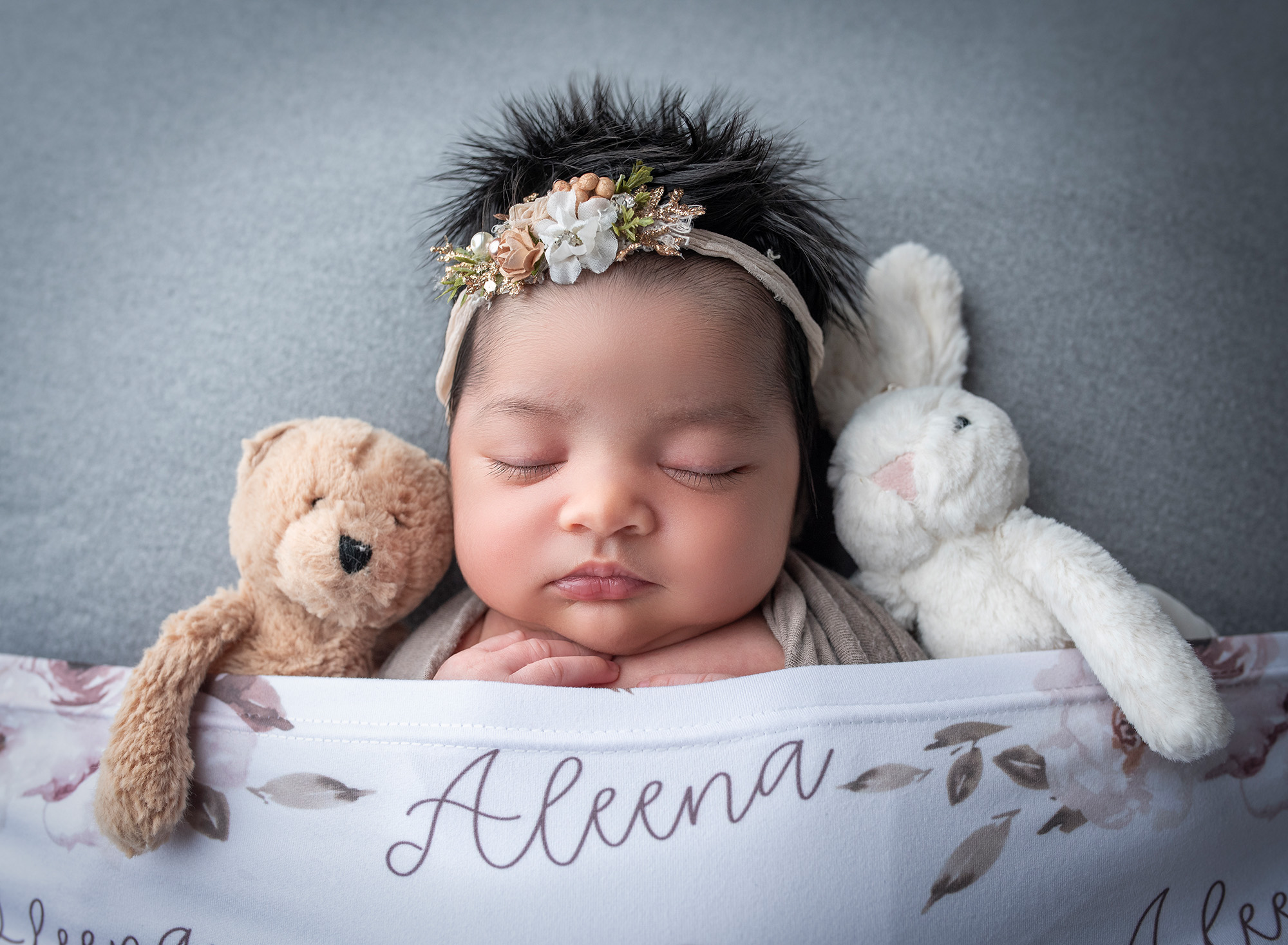 sweet newborn baby girl asleep in between a teddy bear and a bunny
