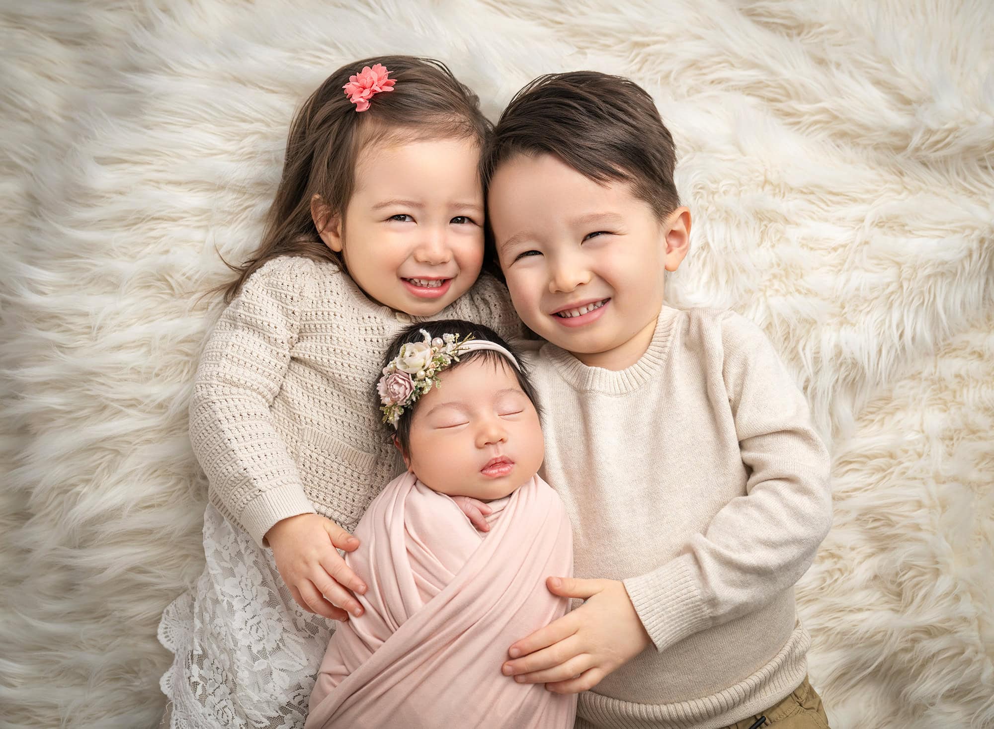 baby and sibling photo two toddlers hold their newborn sister