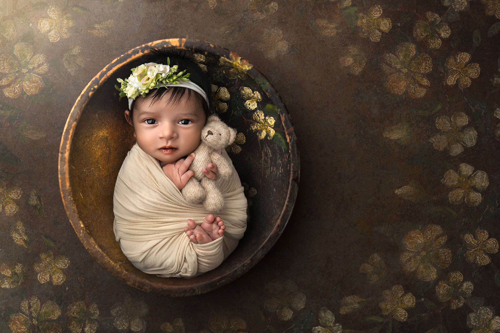 best newborn photographer newborn photographer safely posed baby during photo session cuddling a teddy bear in a rustic bowl with gold flowers