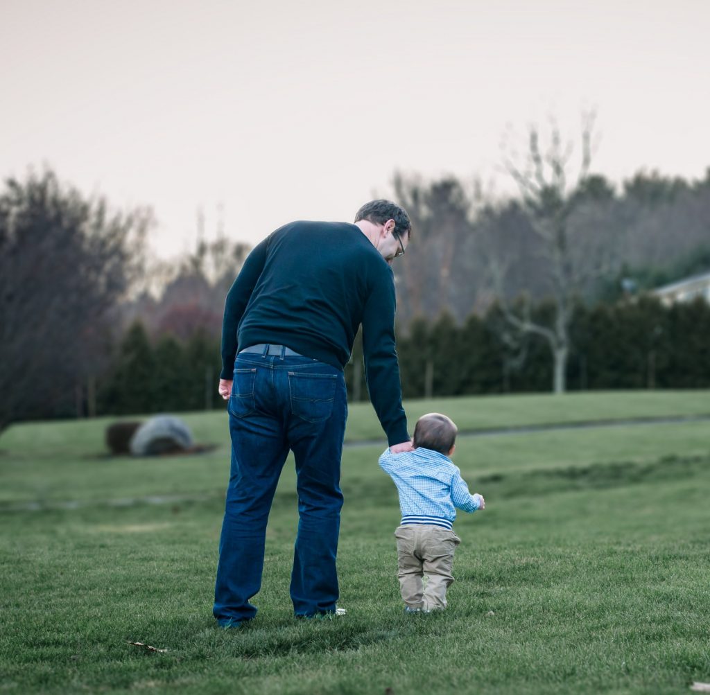 Daddy takes his one-year-old son for a first walk in the grass
