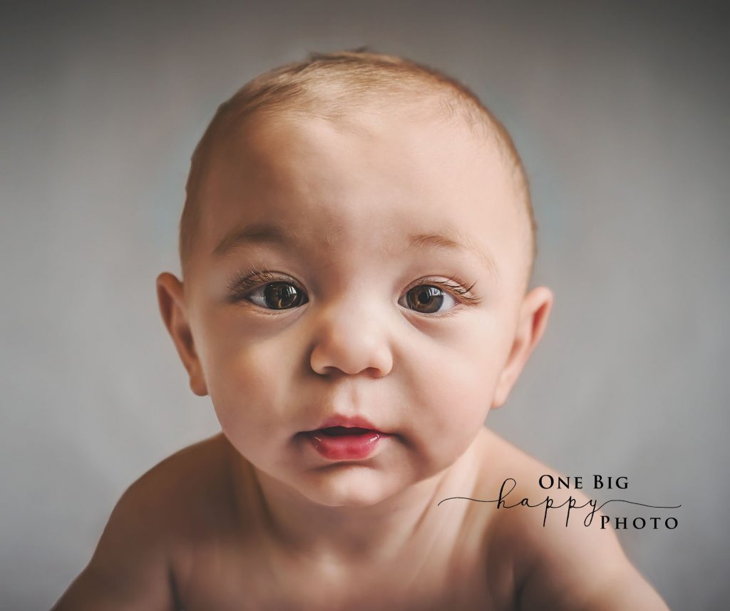 Baby staring into the camera on a grey background