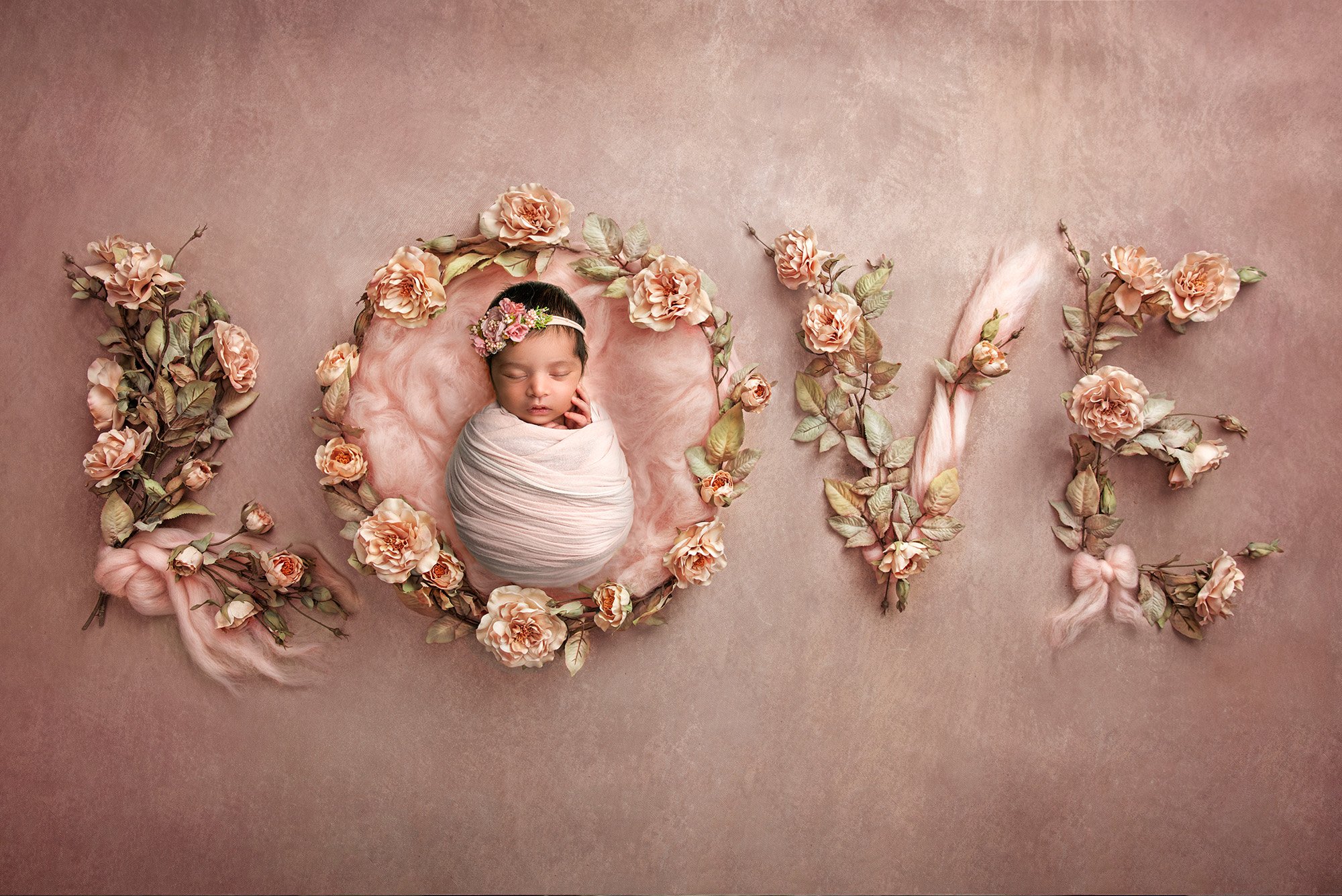 Professional Maternity Newborn Photographer newborn baby girl asleep on a pink background spelling out the word LOVE in flowers