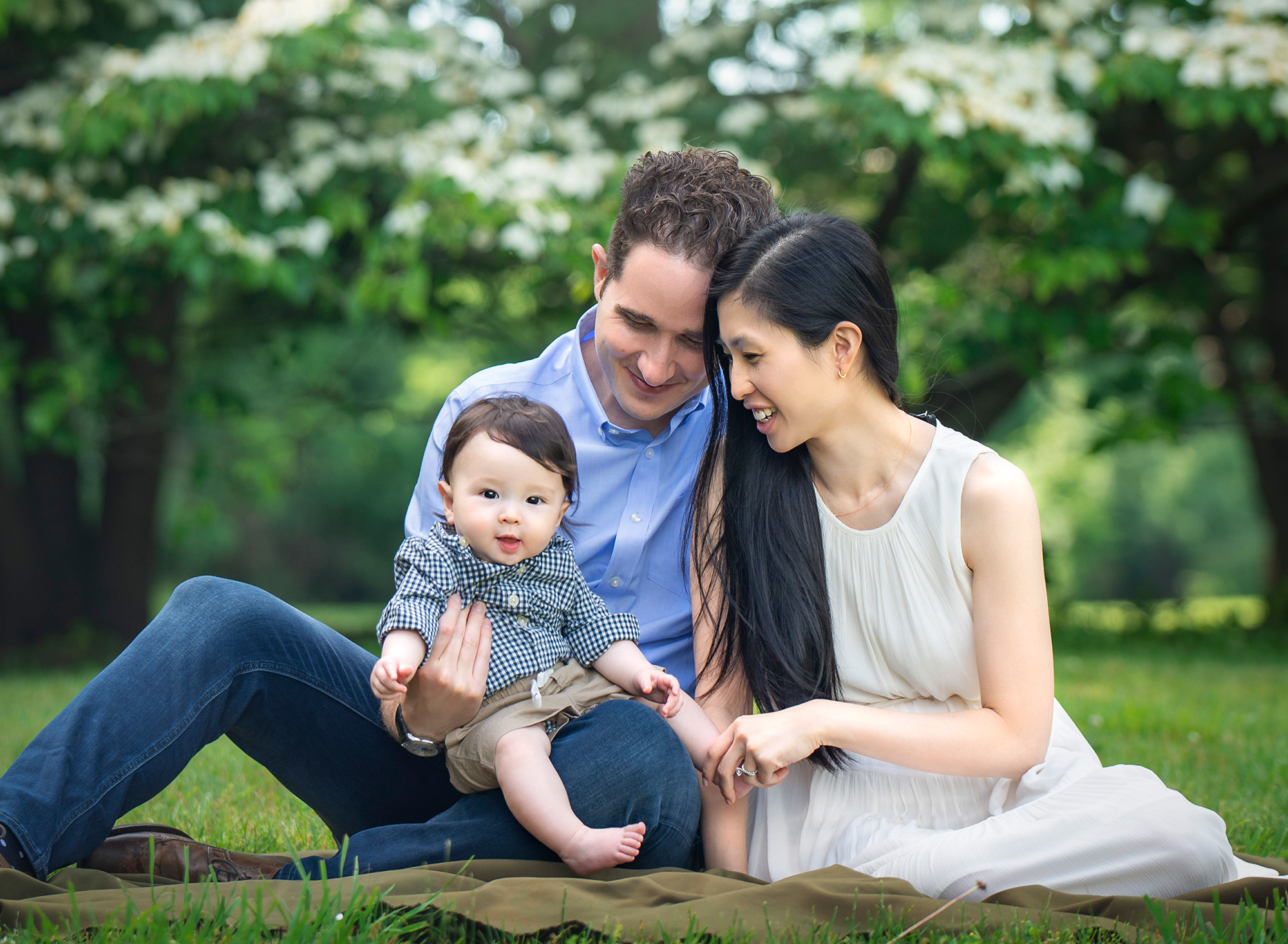 connecticut baby photographer couple sitting in the grass while smiling at toddler son
