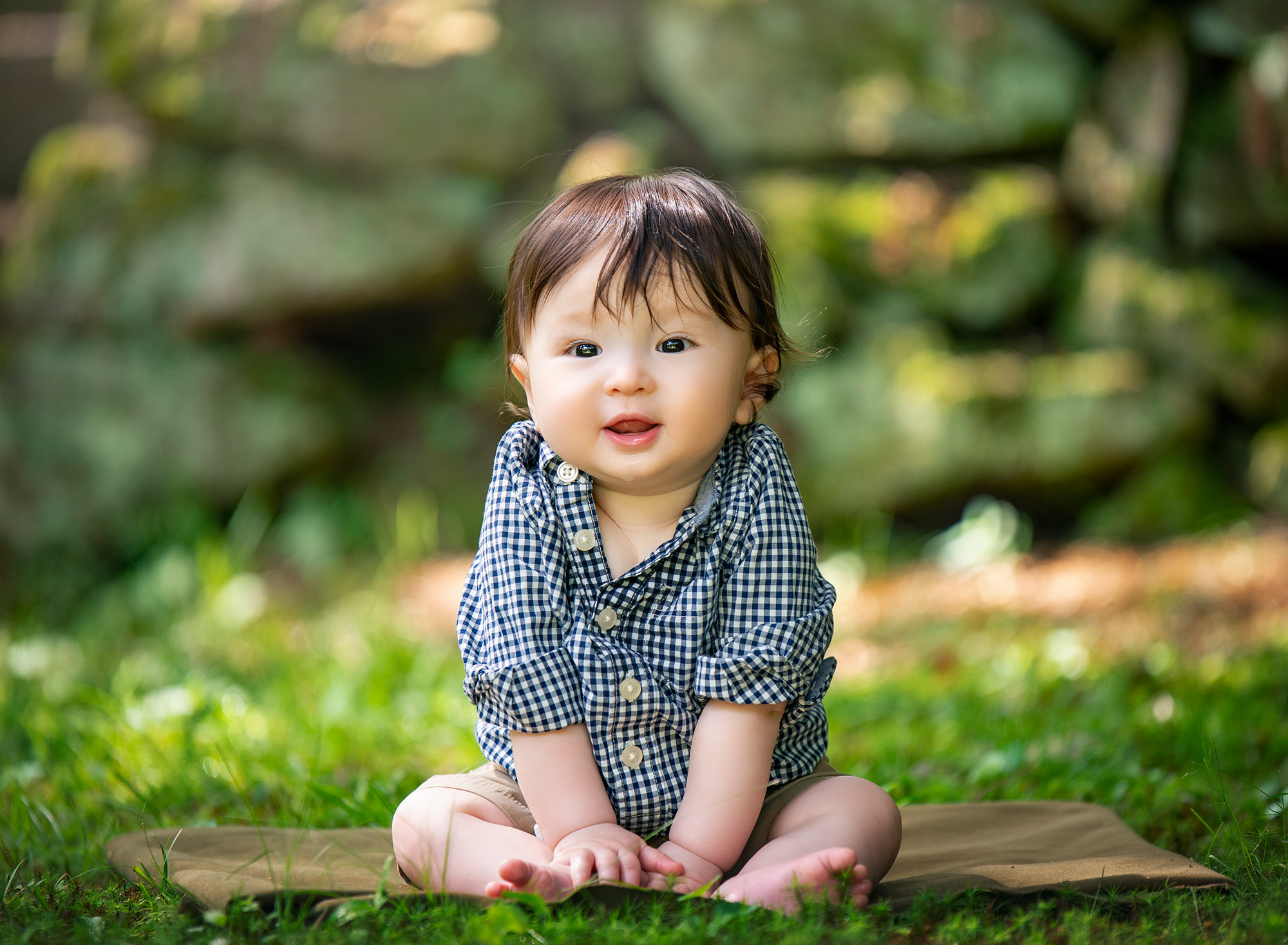 toddler boy dressed in black and white checkered button up sitting on the grass