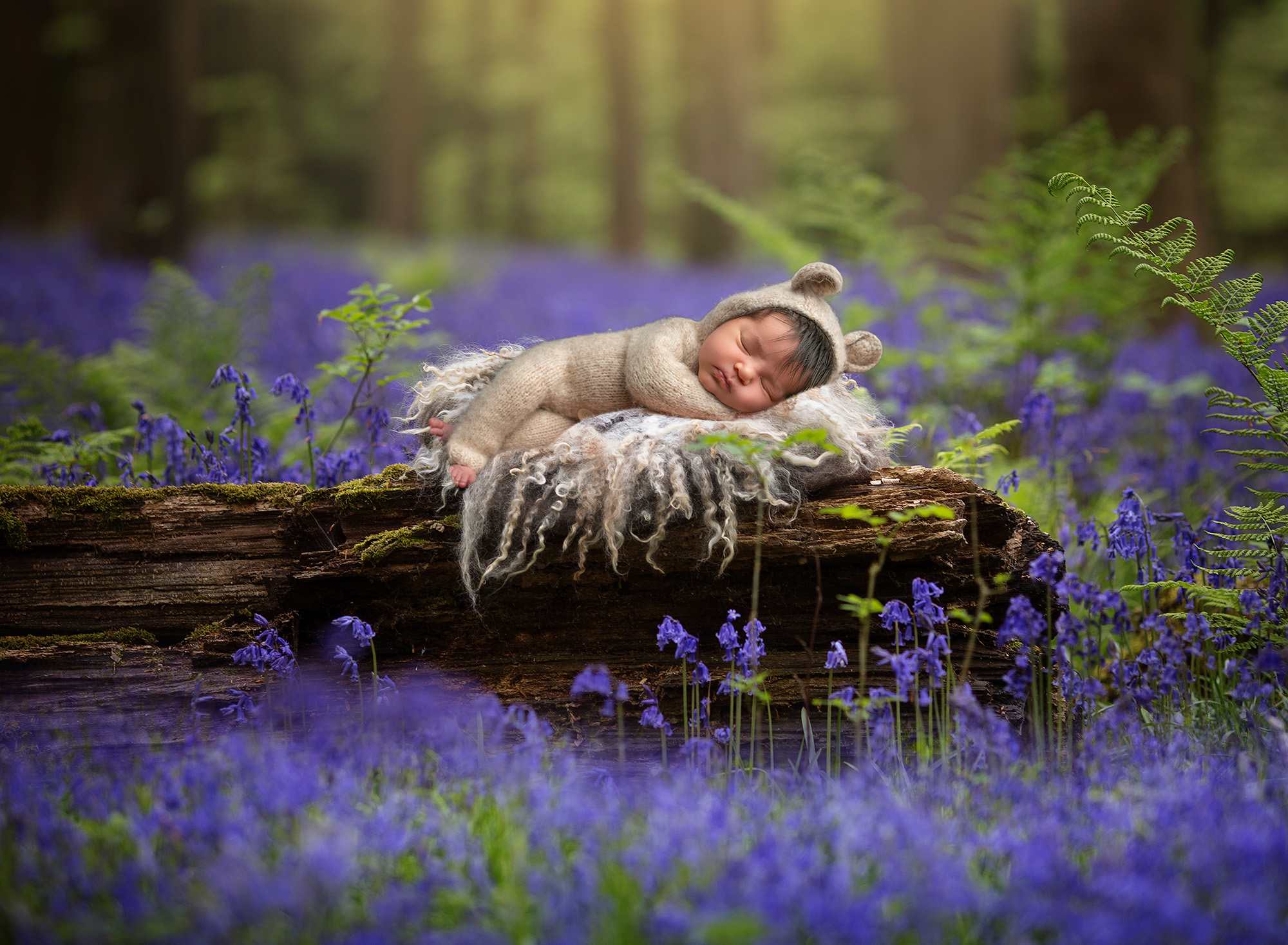 Newborn Photographer in CT baby sleeping in a teddy bear romper on a log in the woods