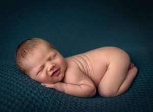 newborn baby boy asleep naked on teal blankets