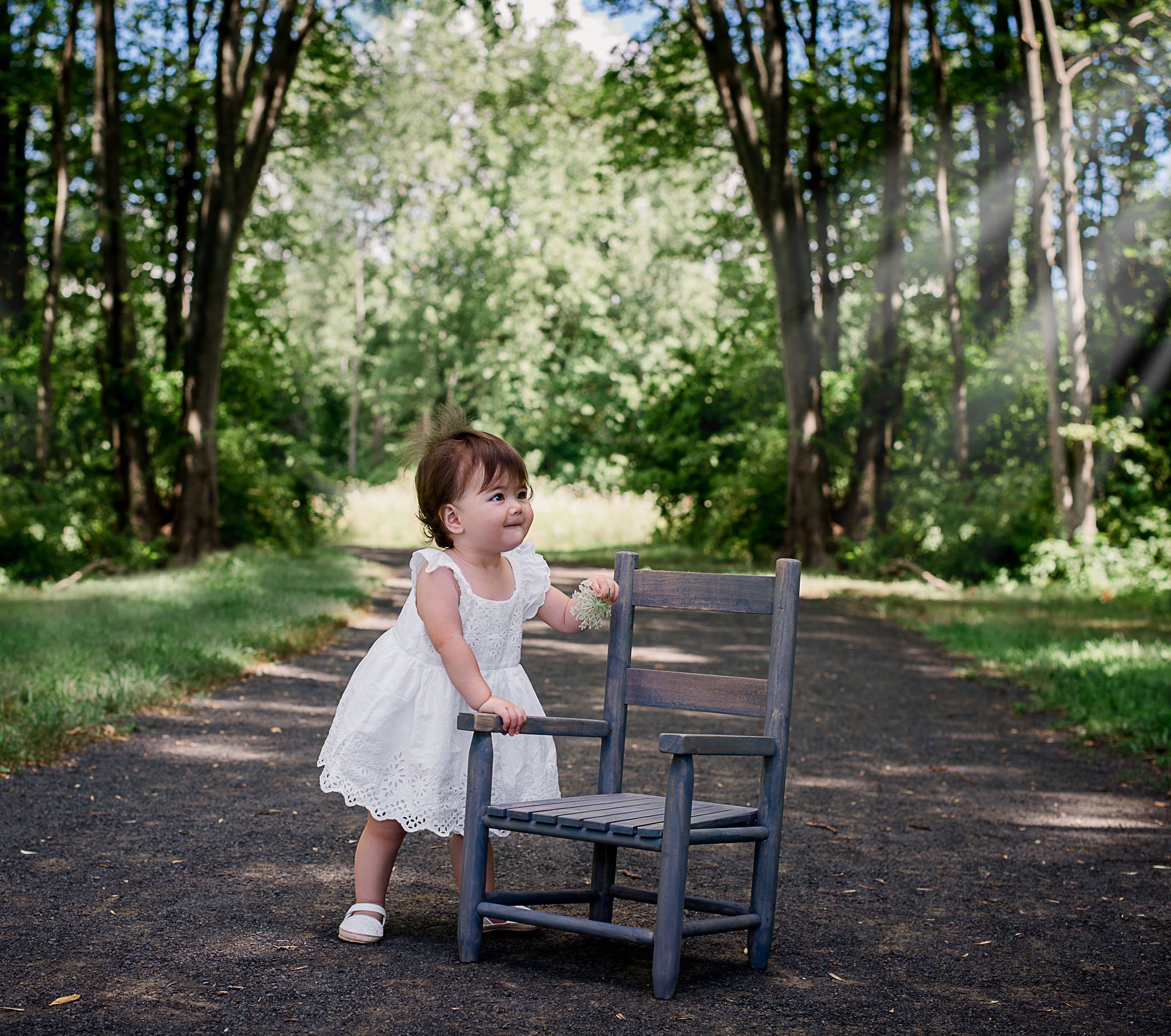 one year old baby girl photo standing next to a child chair in garden One Big Happy Photo
